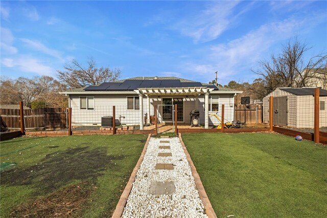 back of property featuring a lawn, central air condition unit, a shed, and solar panels