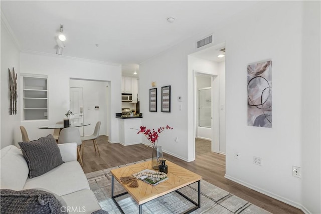 living area with light wood finished floors, visible vents, and baseboards