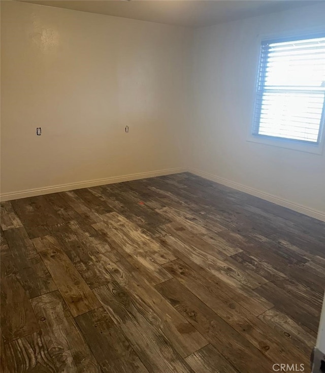 unfurnished room with baseboards and dark wood-type flooring