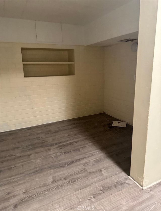 spare room featuring wood finished floors and concrete block wall