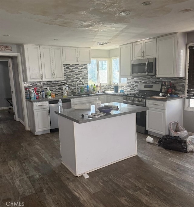 kitchen featuring dark wood-style floors, stainless steel appliances, dark countertops, and white cabinetry