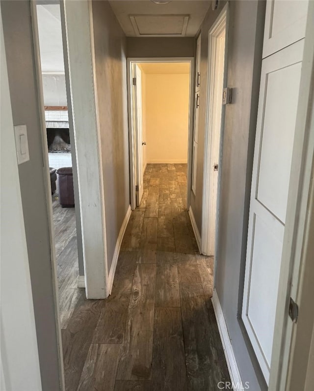 corridor with dark wood finished floors, attic access, and baseboards