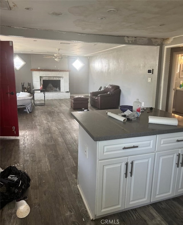 kitchen featuring dark countertops, white cabinets, dark wood finished floors, and open floor plan