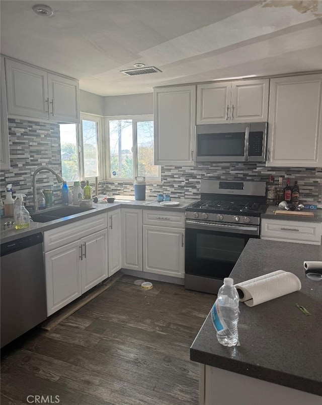 kitchen featuring stainless steel appliances, dark wood-type flooring, a sink, visible vents, and white cabinets