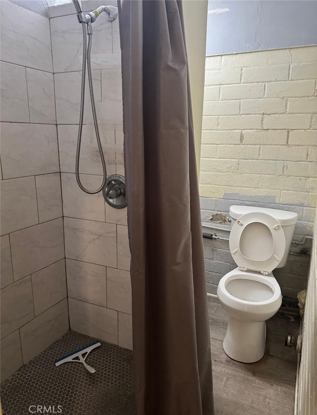 bathroom featuring a stall shower, wood finished floors, and toilet