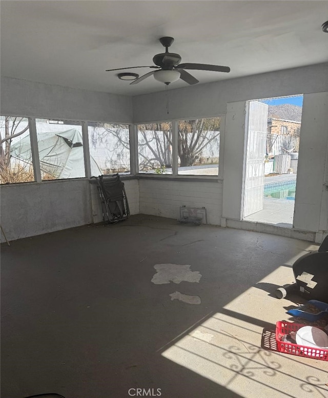 unfurnished sunroom featuring ceiling fan