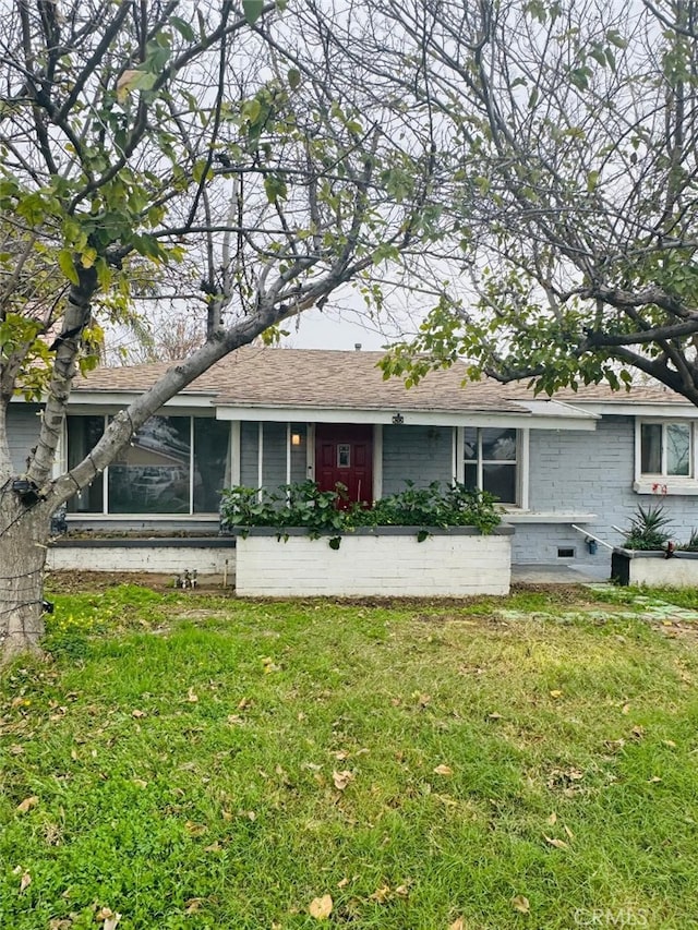 view of front of house featuring a shingled roof and a front yard