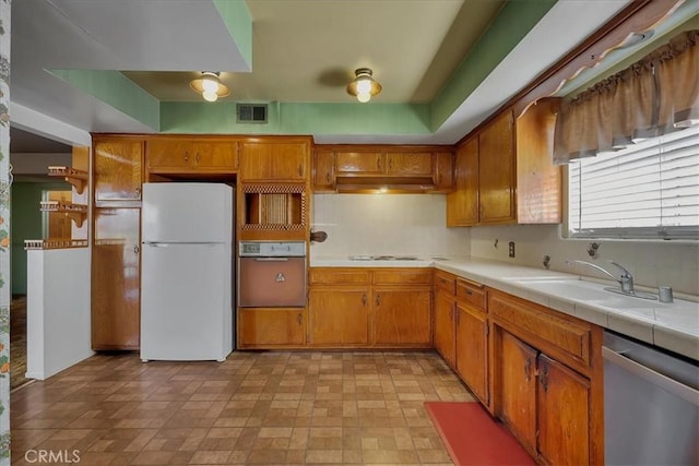 kitchen with white appliances, tile counters, and sink