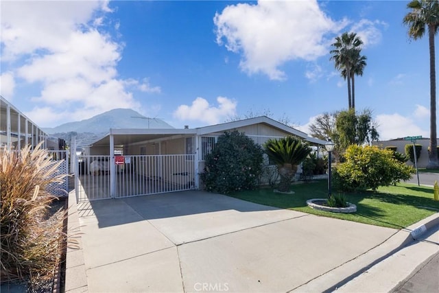 view of front facade featuring a mountain view, a front lawn, and a carport