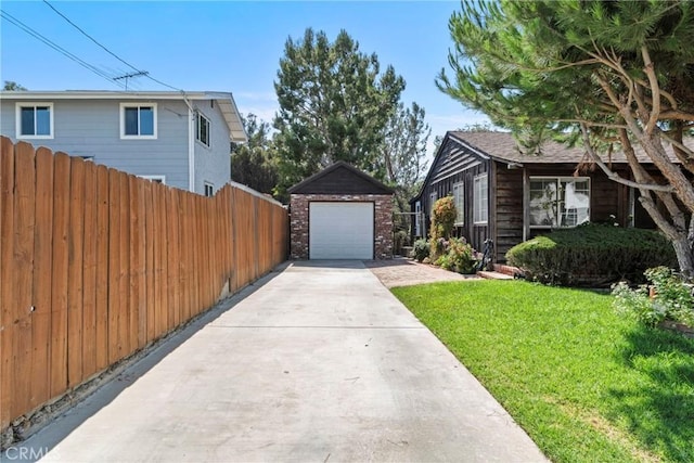 view of side of property with a garage, concrete driveway, an outbuilding, fence, and a yard