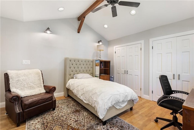 bedroom featuring vaulted ceiling with beams, two closets, and wood finished floors