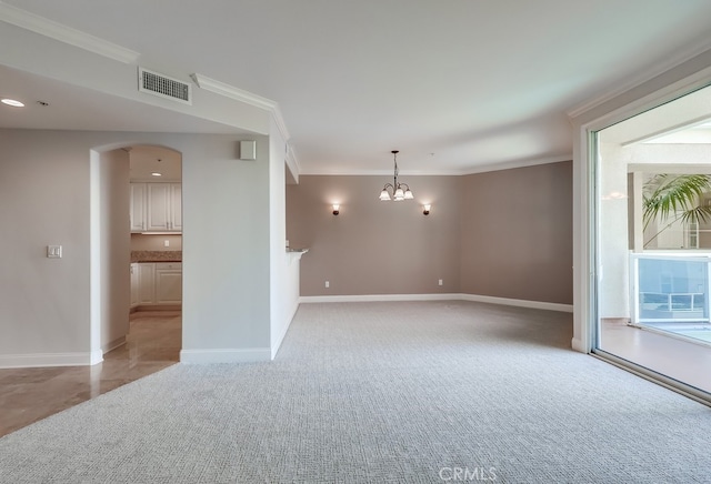 carpeted empty room featuring ornamental molding and a notable chandelier