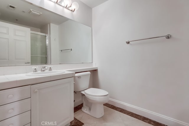 bathroom featuring vanity, tile patterned flooring, toilet, and walk in shower