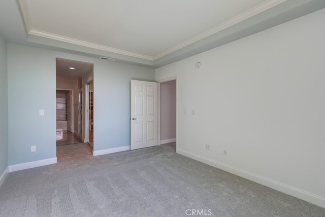 carpeted empty room featuring crown molding and a tray ceiling