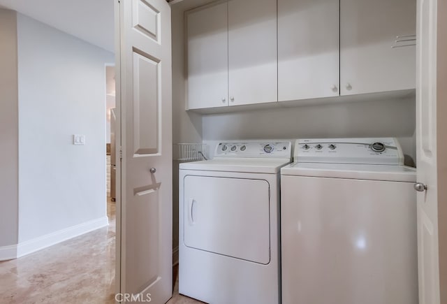 clothes washing area with washer and clothes dryer and cabinets