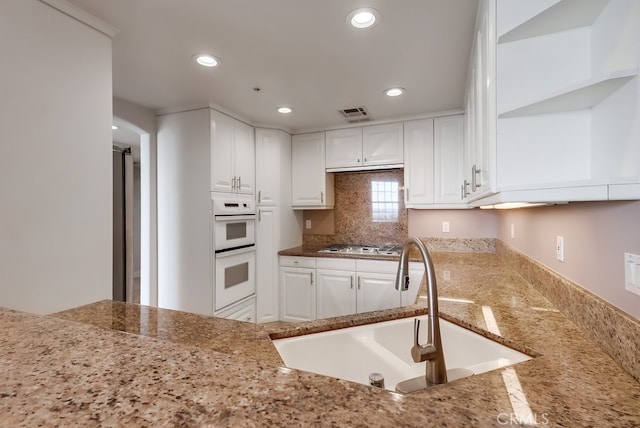 kitchen with white cabinetry, sink, light stone counters, and white appliances