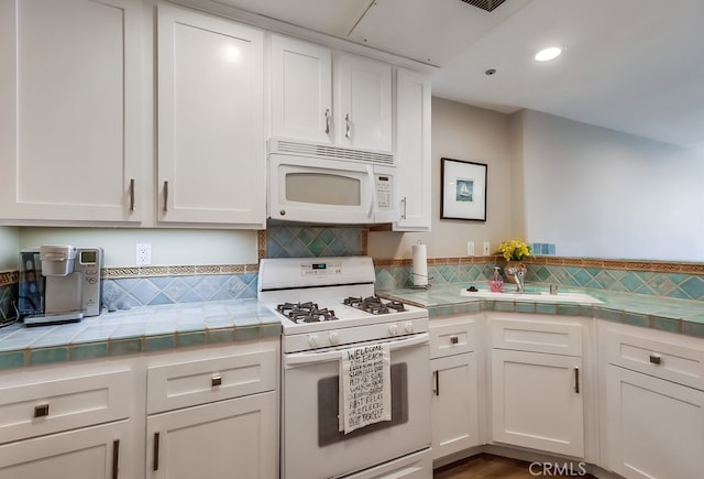 kitchen with tasteful backsplash, white cabinetry, tile countertops, and white appliances