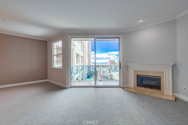 unfurnished living room with a tiled fireplace, crown molding, and carpet floors