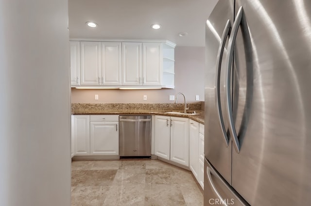 kitchen featuring dark stone countertops, sink, stainless steel appliances, and white cabinets