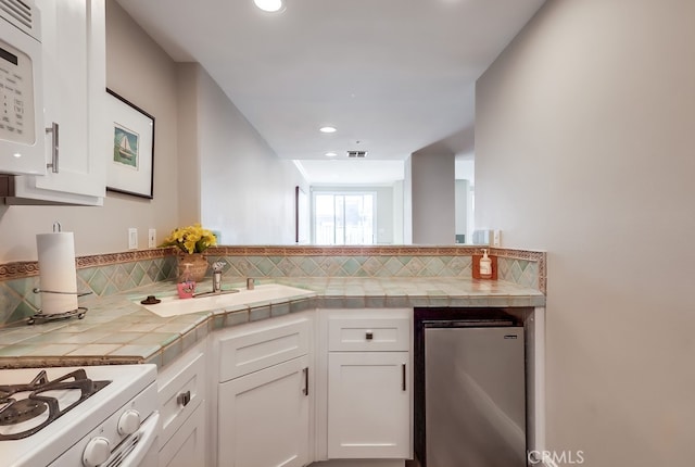 kitchen featuring white cabinetry, white appliances, tile counters, and decorative backsplash