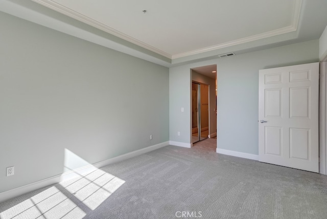 unfurnished room with crown molding, light colored carpet, and a raised ceiling