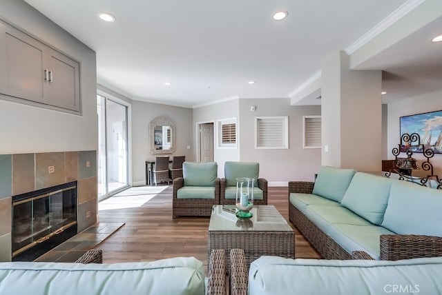 living room with crown molding, a tile fireplace, and light wood-type flooring