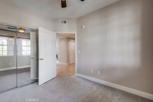 unfurnished bedroom featuring ceiling fan, light colored carpet, and a closet