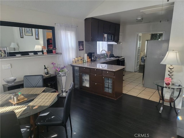 kitchen featuring sink, hardwood / wood-style flooring, kitchen peninsula, stainless steel appliances, and dark brown cabinets