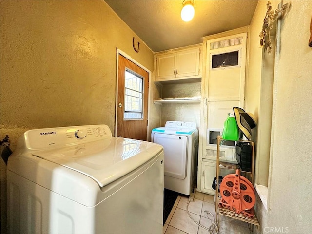 laundry area with cabinets, light tile patterned floors, and washer and clothes dryer