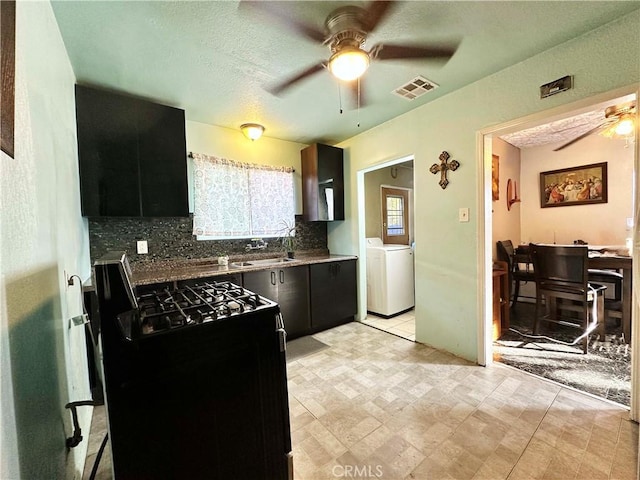 kitchen featuring gas range, ceiling fan, washer / dryer, and a wealth of natural light