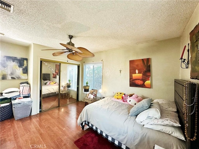 bedroom with a closet, ceiling fan, hardwood / wood-style floors, and a textured ceiling