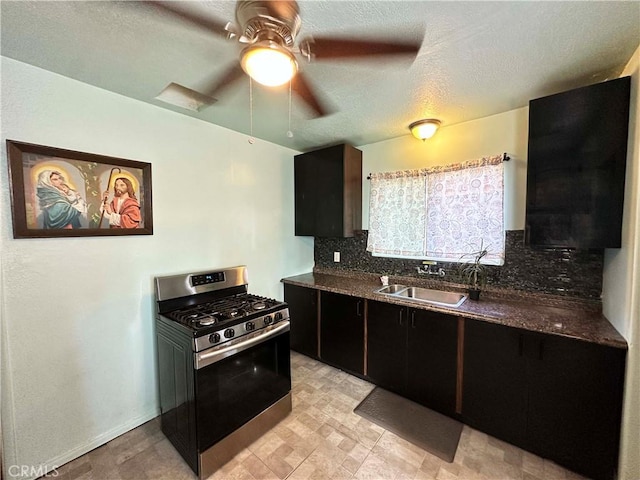 kitchen featuring gas stove, sink, dark stone countertops, and backsplash