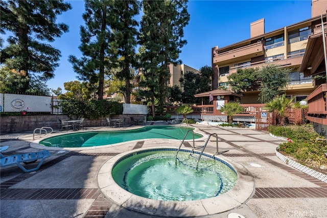 view of swimming pool featuring a hot tub and a patio