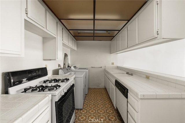 kitchen featuring independent washer and dryer, tile countertops, dishwasher, and white range with gas cooktop