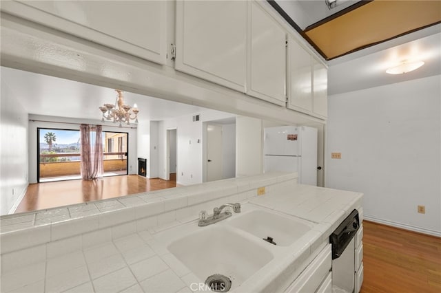 kitchen with sink, white appliances, tile countertops, and white cabinets