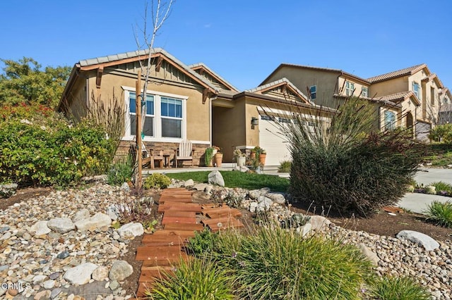 view of front of property with a garage, stone siding, and stucco siding