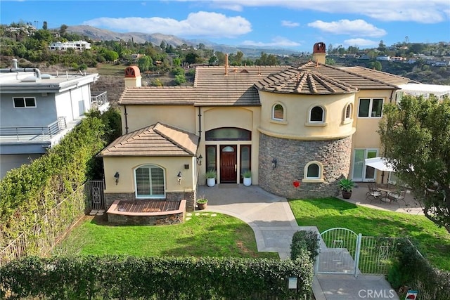 mediterranean / spanish-style house with a mountain view and a front lawn