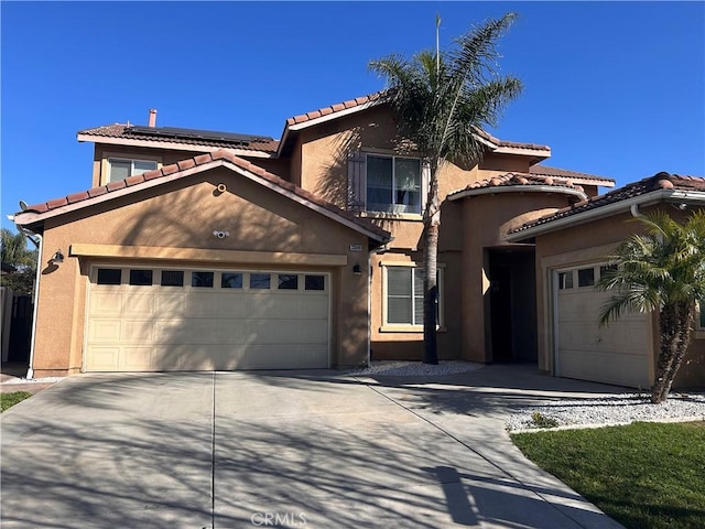 mediterranean / spanish home featuring roof mounted solar panels, a tiled roof, and stucco siding