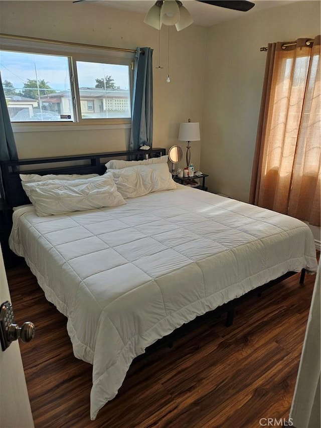 bedroom featuring dark wood-type flooring, ceiling fan, and multiple windows