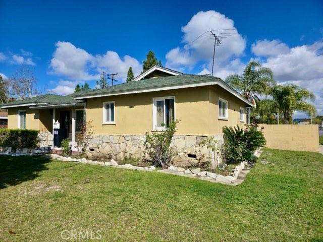 view of side of property with stone siding, stucco siding, a yard, and fence