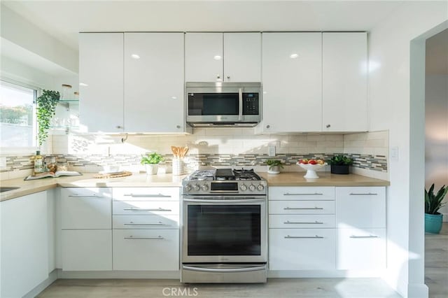 kitchen with tasteful backsplash, appliances with stainless steel finishes, and white cabinets