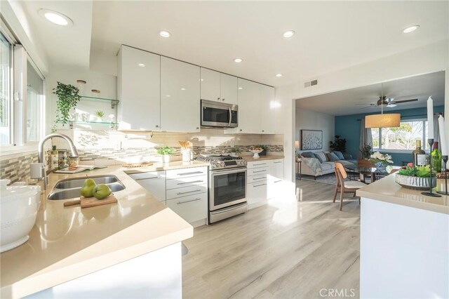 kitchen featuring sink, white cabinetry, tasteful backsplash, light wood-type flooring, and stainless steel appliances