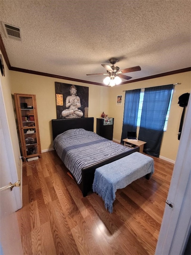 bedroom featuring crown molding, wood-type flooring, a textured ceiling, and ceiling fan