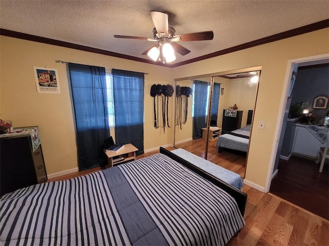 bedroom featuring ceiling fan, wood-type flooring, ornamental molding, a textured ceiling, and a closet