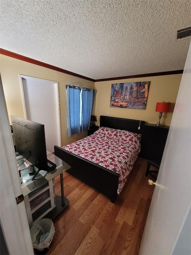 bedroom featuring crown molding, hardwood / wood-style floors, and a textured ceiling