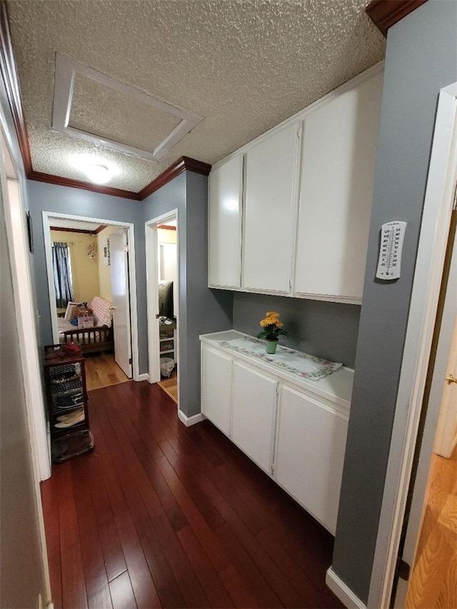 kitchen with ornamental molding, dark hardwood / wood-style flooring, a textured ceiling, and white cabinets