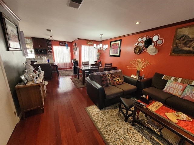 living room with a notable chandelier, dark wood-type flooring, and ornamental molding