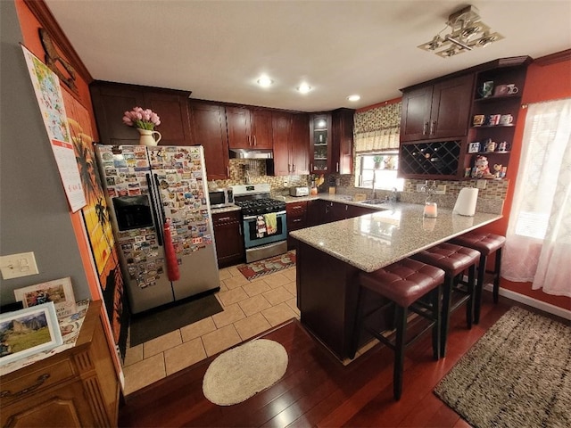 kitchen with decorative backsplash, appliances with stainless steel finishes, a breakfast bar, and kitchen peninsula