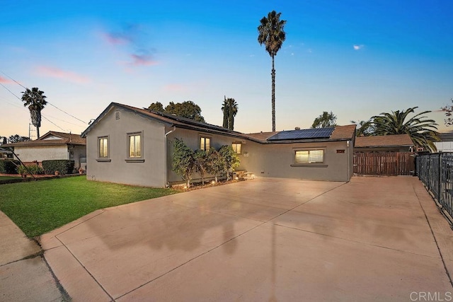 ranch-style house featuring a lawn and solar panels