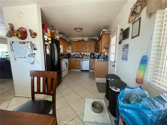 kitchen with black refrigerator, white electric stove, stainless steel dishwasher, light tile patterned floors, and plenty of natural light